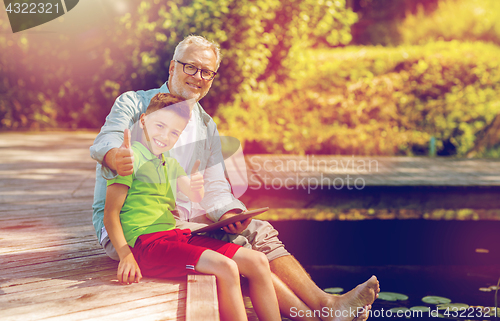 Image of grandfather and boy with tablet pc on river berth