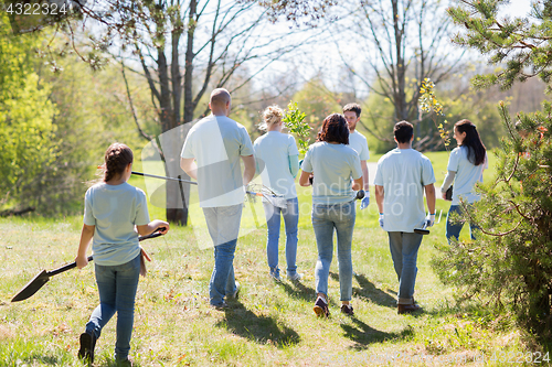 Image of happy volunteers with seedlings and garden tools