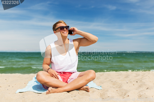 Image of smiling man calling on smartphone on summer beach