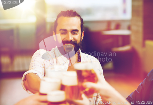 Image of man clinking beer glass with friends at restaurant