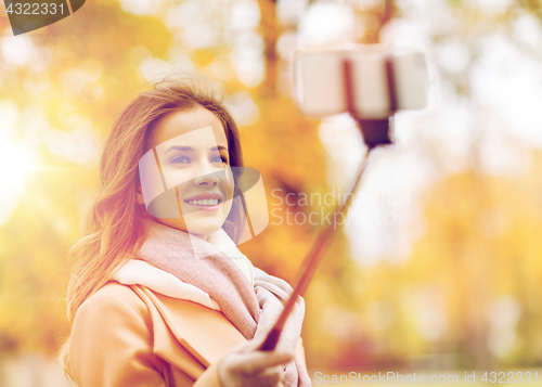 Image of woman taking selfie by smartphone in autumn park