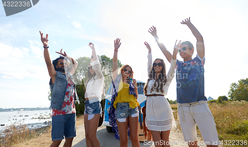 Image of smiling hippie friends having fun near minivan car