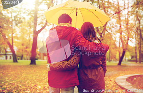 Image of happy couple with umbrella walking in autumn park