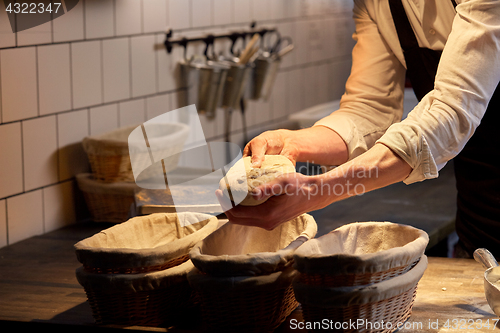 Image of baker with dough rising in baskets at bakery