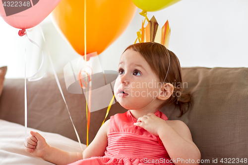 Image of happy baby girl in crown on birthday party at home
