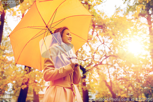 Image of happy woman with umbrella walking in autumn park