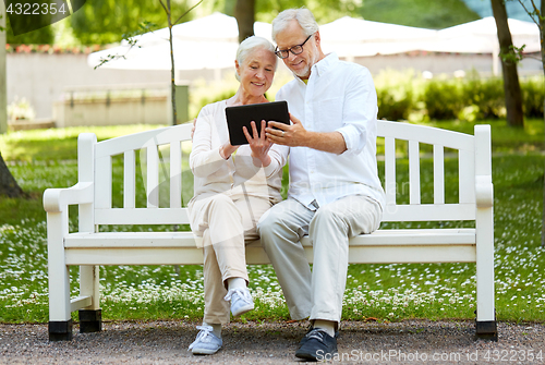 Image of happy senior couple with tablet pc in city park