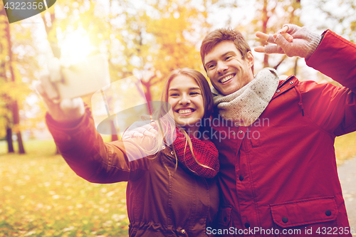 Image of couple taking selfie by smartphone in autumn park