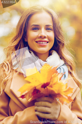 Image of beautiful woman with maple leaves in autumn park