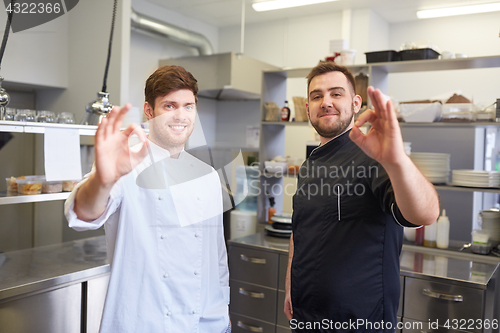 Image of happy chefs at restaurant kitchen showing ok sign