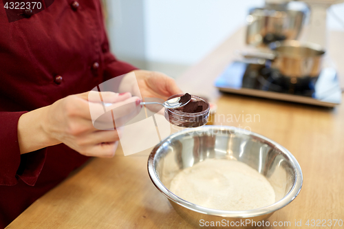 Image of chef hands adding food color into bowl with flour