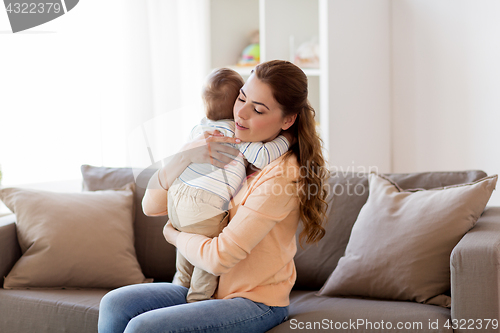 Image of happy young mother hugging little baby at home