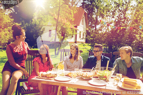 Image of happy friends having dinner at summer garden party