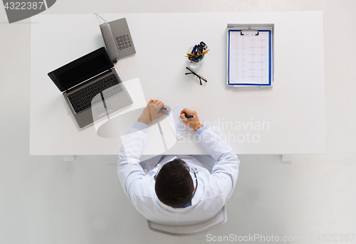 Image of doctor with prescription and laptop at clinic