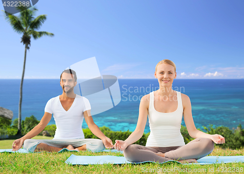 Image of couple doing yoga in lotus pose outdoors