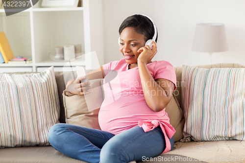 Image of pregnant woman in headphones with smartphone