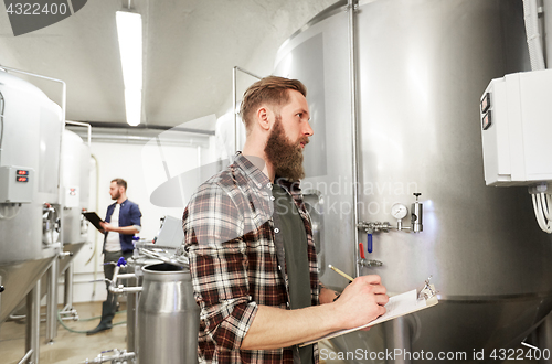 Image of men with clipboard at craft brewery or beer plant