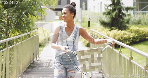 Image of Young girl walking with bicycle