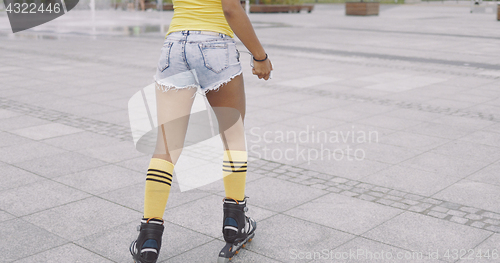 Image of Crop woman roller skating at street