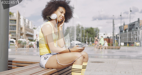 Image of Model in headphones sitting on bench