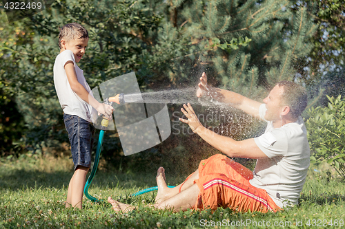 Image of Happy father and son playing in the garden at the day time.