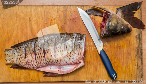 Image of The brushed and cut fish lies on the cutting board, next to it lies a knife