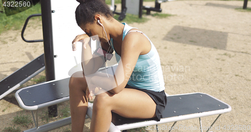 Image of Tired sportswoman on bench in park