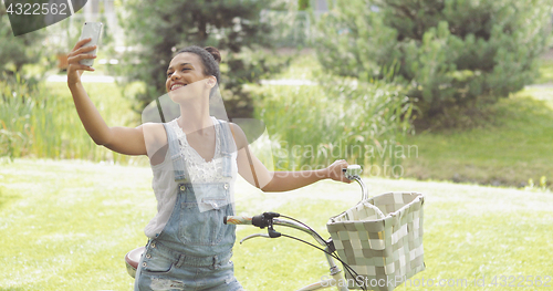 Image of Cheerful woman taking selfie in park