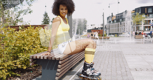 Image of Stylish woman in rollers posing on bench