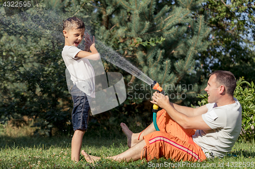 Image of Happy father and son playing in the garden at the day time.