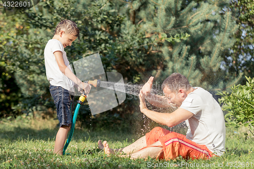 Image of Happy father and son playing in the garden at the day time.