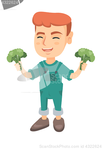 Image of Little caucasian boy laughing and holding broccoli