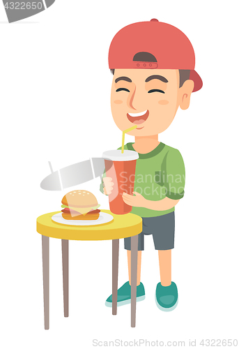 Image of Little boy drinking soda and eating cheeseburger.