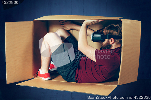 Image of Introvert concept. The man sitting inside box with glasses of virtual reality. Future technology concept