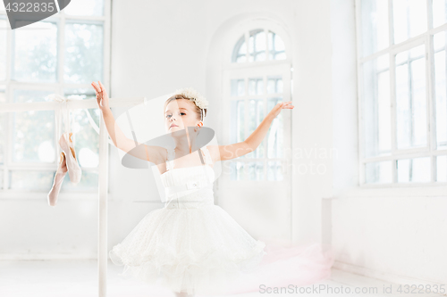 Image of Little ballerina girl in a tutu. Adorable child dancing classical ballet in a white studio.