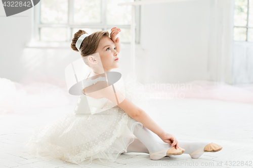 Image of The little balerina in white tutu in class at the ballet school