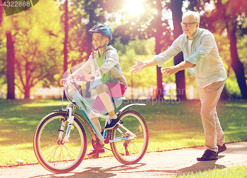 Image of grandfather and boy with bicycle at summer park