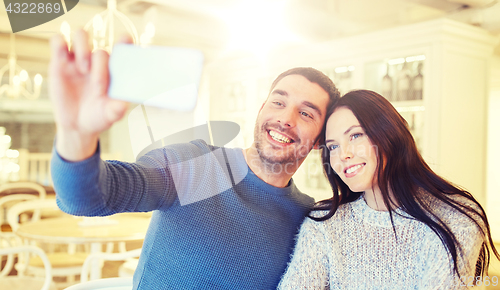 Image of couple taking smartphone selfie at cafe restaurant