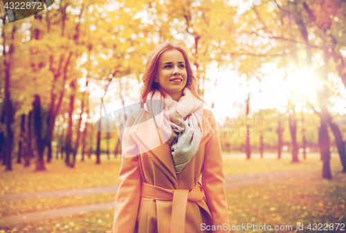 Image of beautiful happy young woman walking in autumn park