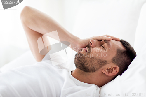 Image of man in bed at home suffering from headache