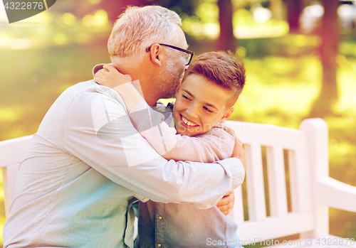 Image of grandfather and grandson hugging at summer park