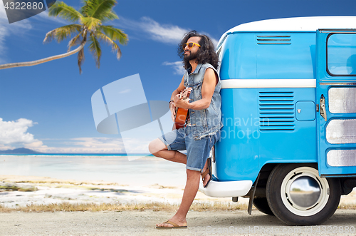 Image of hippie man playing guitar at minivan car on beach