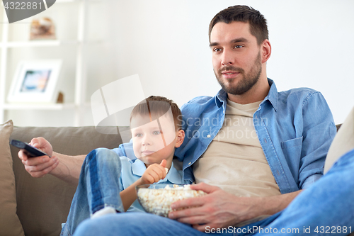 Image of father and son with popcorn watching tv at home