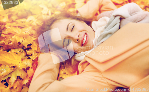 Image of beautiful happy woman lying on autumn leaves