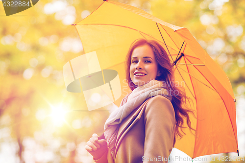 Image of happy woman with umbrella walking in autumn park