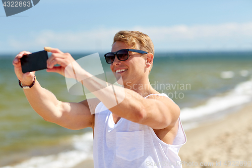 Image of man taking selfie by smartphone on summer beach