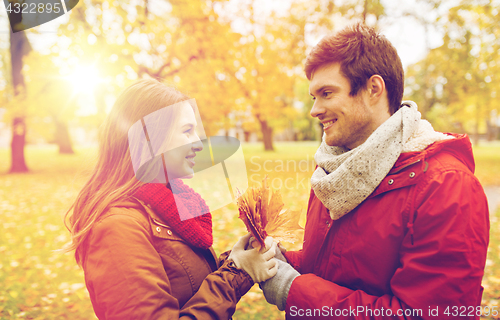 Image of happy couple with maple leaves in autumn park