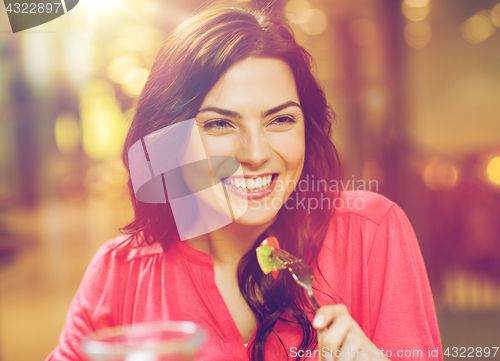 Image of happy young woman having dinner at restaurant