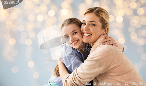 Image of happy girl with mother hugging over lights