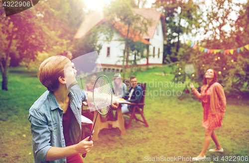 Image of happy friends playing badminton at summer garden